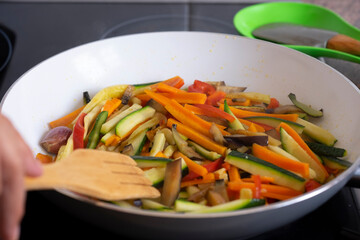 Colored mix of filleted fresh vegetables, courgettes, carrots, peppers and eggplants sautéed in a pan to be used for rolls
