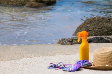 tanning lotion, sunglasses, hat and bikini on the beach