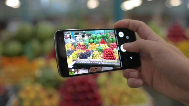 Man takes photo of fruits and vegetables in the local market by his phone