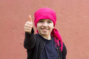 girl sick with cancer with head scarf and making ok sign with hands