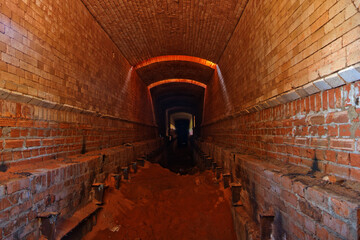 Old ruined brick vaulted tunnel. Dark passage. Underground communication