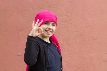 girl sick with cancer with head scarf and making ok sign with hands
