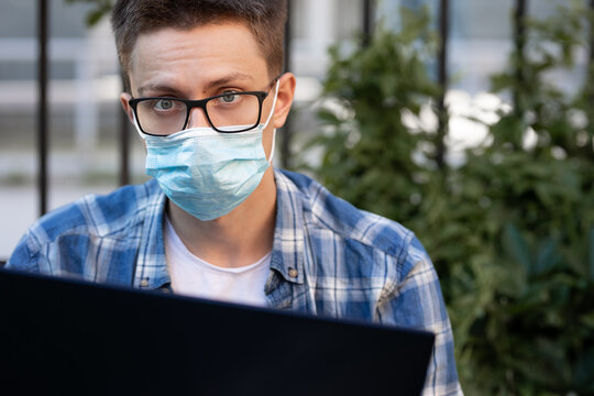 guy in antivirus mask outdoors working on laptop