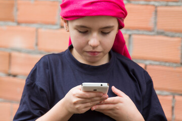 girl sick with cancer and with a headscarf using the mobile phone