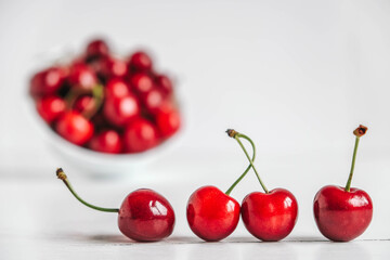 Fresh juicy red cherries in a white plate on the white wooden background. Copy, empty space for text