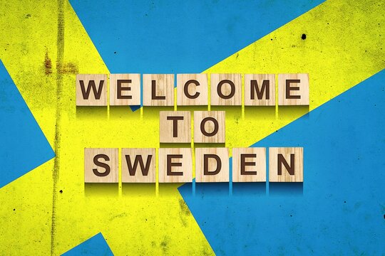 Welcome to Sweden. The inscription on wooden blocks on the background of the flag of Sweden. - Powered by Adobe