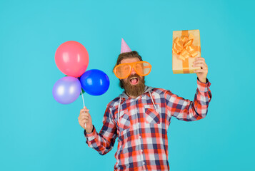 Celebrating concept. Happy birthday. Party time. Holidays and celebration, party. Happy man with present box and balloons.