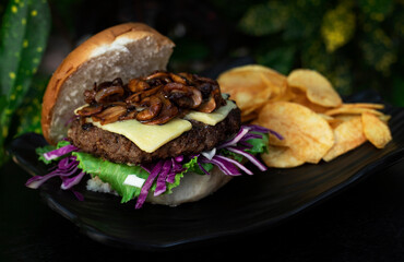beef burger with chips on a black plate dark background 