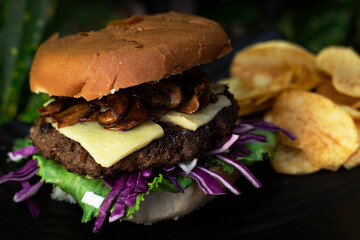 beef burger with chips on a black plate dark background 