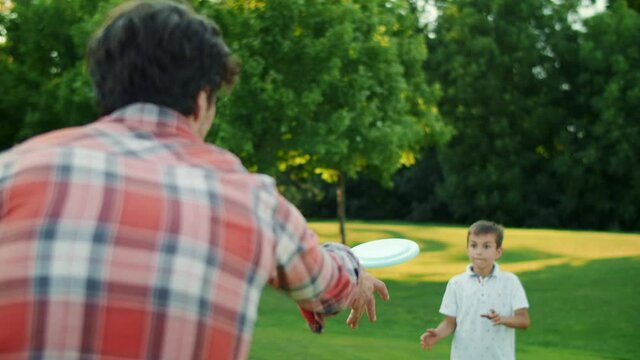 Family playing frisbee in field. Parents and children throwing frisbee disc