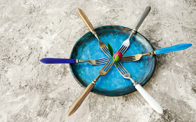 Colored set of kitchen plate with forks on a gray background.