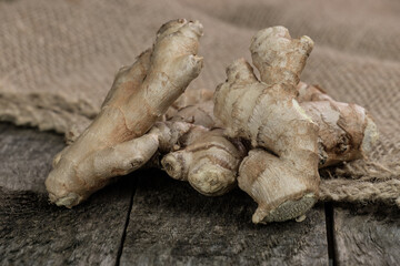 Ginger / Ingwer (lat.: Zingiber officinale) Wurzel / Knolle auf altem rustikalen Holz und auf Jute-Stoff