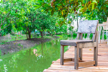 Fototapeta na wymiar Wooden chairs on the balcony of the orchard with a canal for sitting and resting