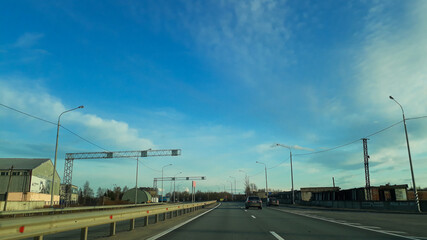 A road or highway leading to the horizon. View from the car window. Northern dim summer, blue sky with white clouds. Journey, the way home.