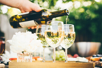 White wine being poured into glass. Concept of celebration, party outdoors.
