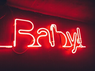 Bright red neon sign, outlined baby word in bar. Night club and bar party lights