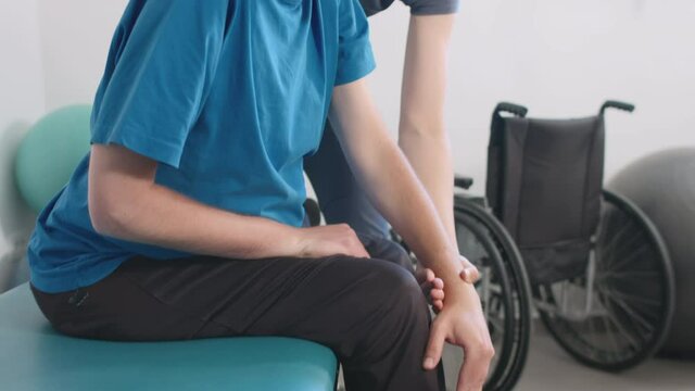 Physiotherapist exercising with disabled person on a therapy table.