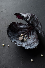 Vertical image.Red cabbage foliage and decorative beads in it, black surface