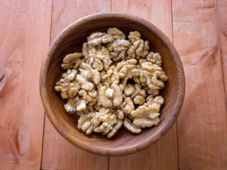 Walnuts in a wooden bowl on a wooden table.