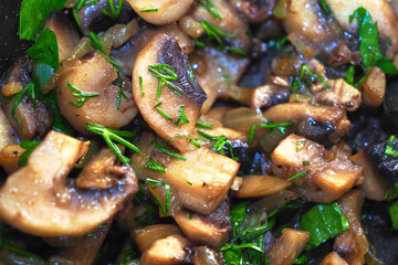 Fried champignon with herbs in a pan.
