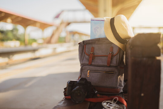Map in Backpack ,Mobile phone with earphone and hat at the train station with a traveler.sun set, Travel concept.