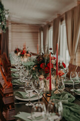 decor of a festive wedding table decorated with a large bouquet, lanterns and candles in green and red colors.