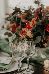 decor of a festive wedding table decorated with a large bouquet, lanterns and candles in green and red colors