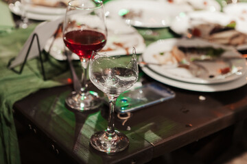 a glass filled with red wine stands on a table next to other glasses on a table with a white tablecloth
