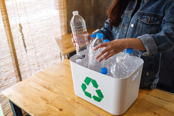 A woman collecting and separating recyclable garbage plastic bottles into a trash bin at home