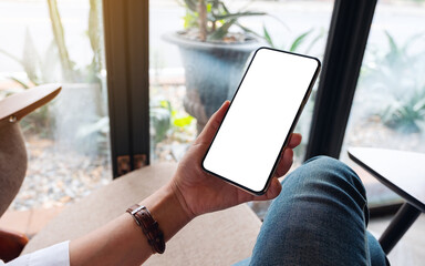 Mockup image of a woman holding mobile phone with blank white desktop screen