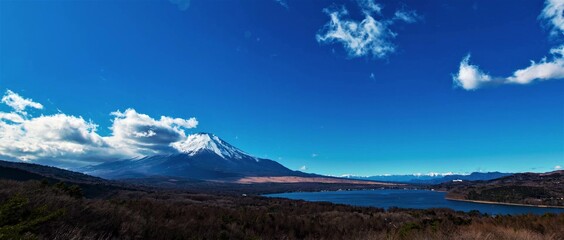 View of famous Mount Fuji and Yamanaka Lake landscape from a meadow with blue sky.
