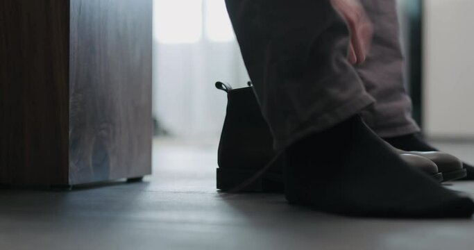 Young man put on his brown leather chukka boots indoor