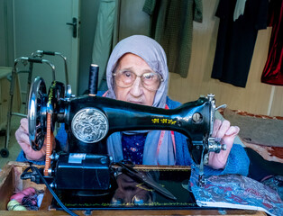 Arabic muslim old woman using old sewing machine