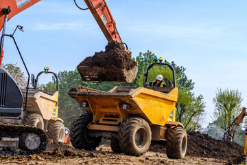 Excavator loads earth into tipper truck on construction site © Chris Mann