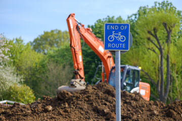 Excavator moves earth behind cycle route sign