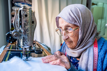 Arabic muslim old woman using old sewing machine