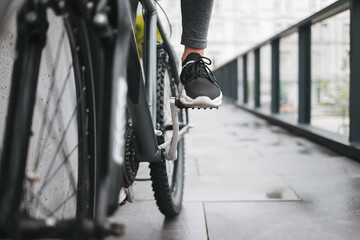 Naklejka premium Girl's foot on the bicycle pedal. Woman rides a city on the bike