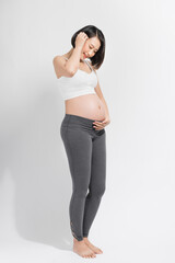 Naklejka premium Pregnant woman in dress holds hands on belly on a white background