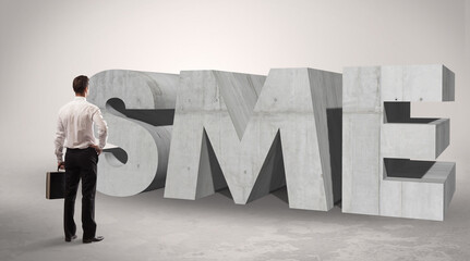 Rear view of a businessman standing in front of SME abbreviation, modern technology concept