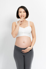 Pregnancy Secrets. Happy Pregnant Lady Gesturing Hush Sign Putting Finger On Lips Standing On White Studio Background. Free Space