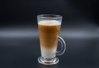 A studio shot of three-layered coffee drink and chocolate chip cookies in black grey background