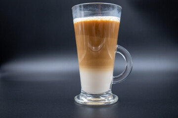 A studio shot of three-layered coffee drink and chocolate chip cookies in black grey background