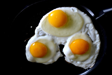 on a black background. Fried three eggs.