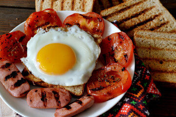 fried egg with sausages, grilled bread and tomatoes with spices, background