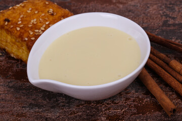 Condenced milk in the bowl with sinnamon and pastry