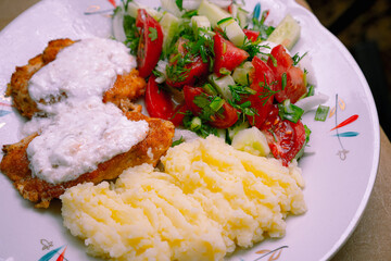 Mashed potatoes, chicken and salad on a plate
