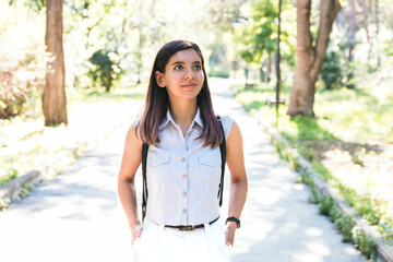 cheerful young woman in light clothes walking alone in park enjoying nature and respecting social distancing rules