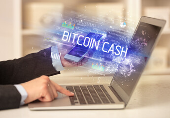 Closeup of businessman hands working on laptop with BITCOIN CASH inscription, succesfull business concept