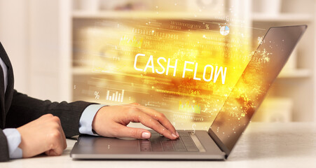Closeup of businessman hands working on laptop with CASH FLOW inscription, succesfull business concept