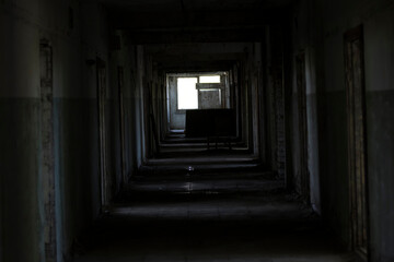 A dark corridor in an abandoned building. A cluttered corridor in ruins. Abandoned building. Horror. Dark room. Long passage.